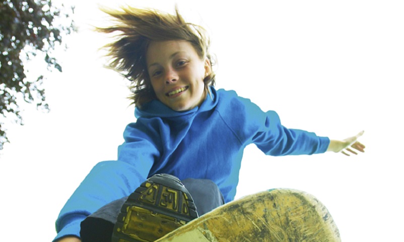AEGY1X YOUNG TEENAGE GIRL ON A SKATEBOARD DOING AN AERIAL LEAP